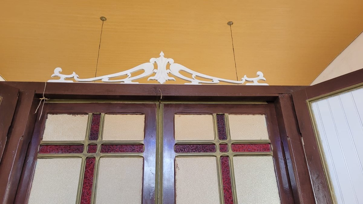 Detalhe do frontão ornamental sobre a porta principal, com vitral em cruz